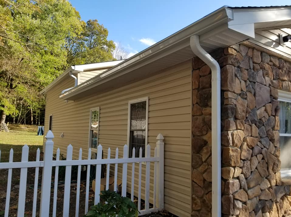 Tan vinyl siding with stone veneer accent and white seamless gutters